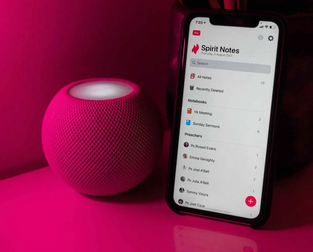 iPhone standing next to pink Bluetooth speaker